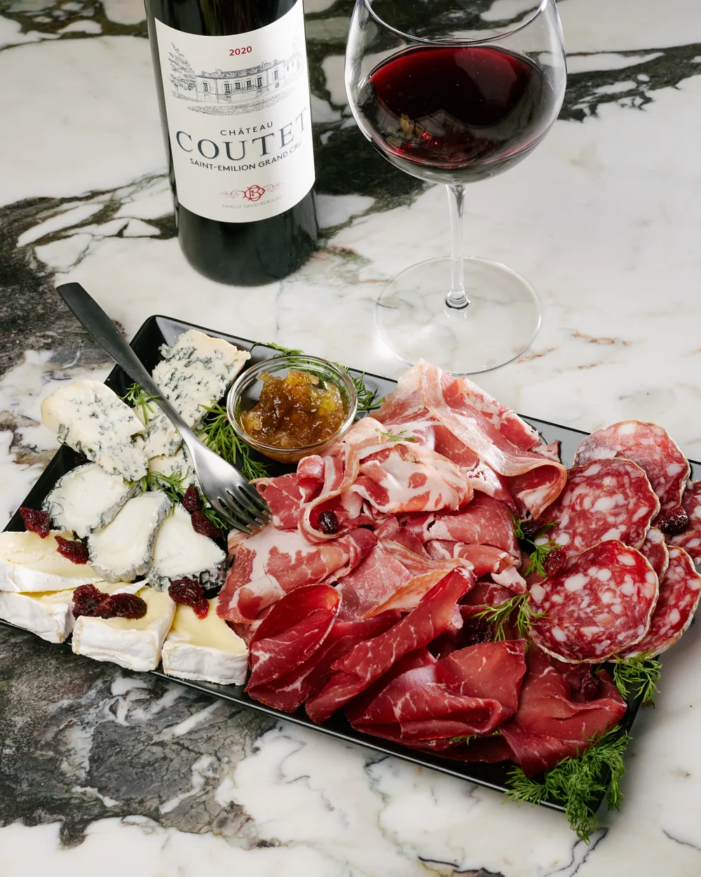 Tagliere di salumi e formaggi con un calice di rosso alla Vinothèque RSVP